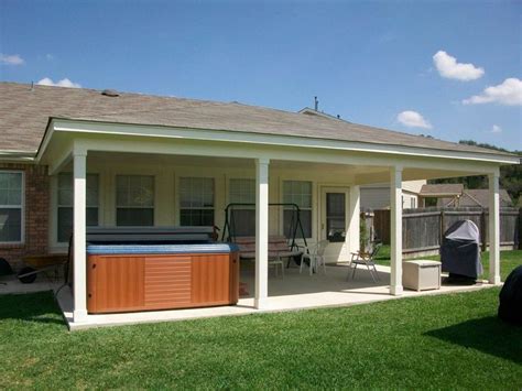 a backyard with a hot tub on the grass and a grill in the back yard