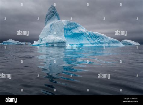 Huge iceberg with a cruise ship for size comparison, set off vibrantly ...