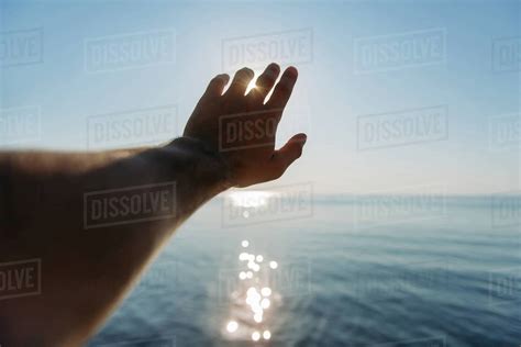 Man's hand reaching for the sun - Stock Photo - Dissolve