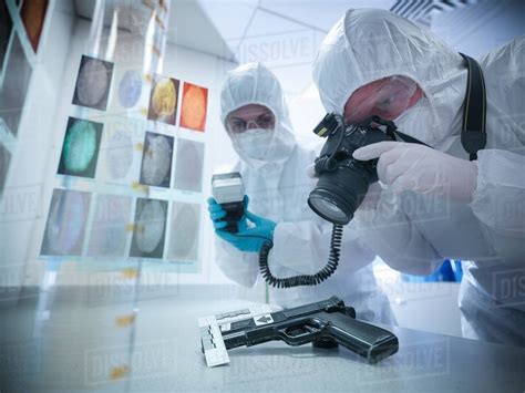 Forensic scientists photographing fingerprints on gun in laboratory - Stock Photo - Dissolve