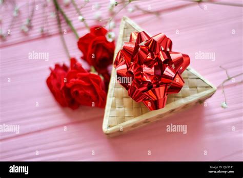 Top view triangle box with red bow. Red rose flowers on pink wooden desk Stock Photo - Alamy