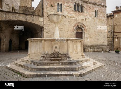 Medieval fountain and San Silvestro Church façade in the main square of the town of Bevagna in ...