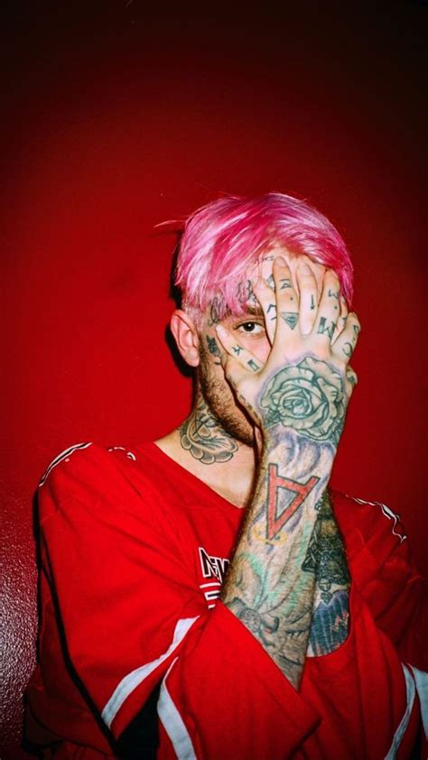 a man with pink hair and tattoos covering his face in front of a red wall