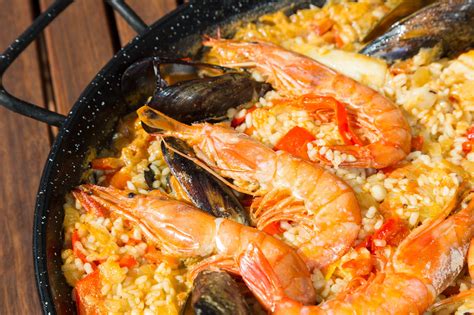 a pan filled with rice and shrimp on top of a wooden table