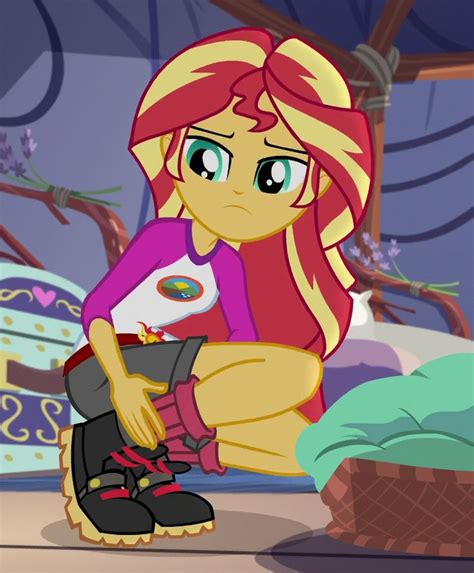 a little pony sitting on top of a bed next to a pile of clothes and shoes