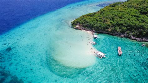 Aerial view of sandy beach with tourists swimming in beautiful clear sea water of the Sumilon ...