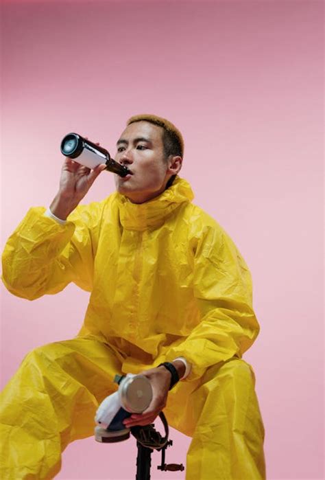 Man in Yellow Coveralls Drinking Beer · Free Stock Photo