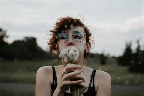 Selective focus photography of a woman blowing dandelion flowers | Pixeor