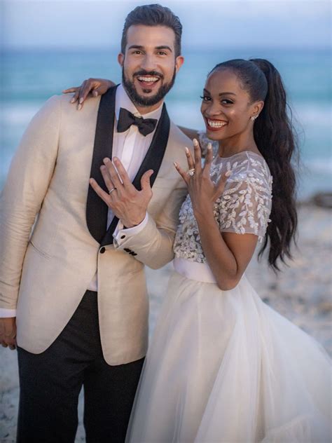 a man in a tuxedo standing next to a woman wearing a dress on the beach