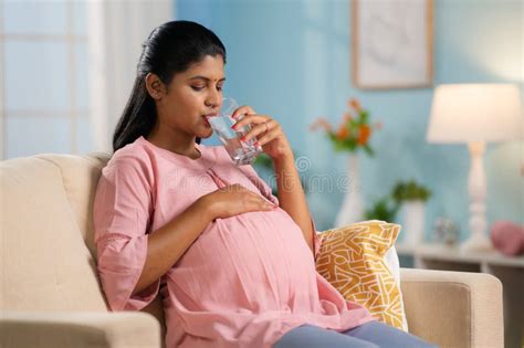 Indian Pregnant Woman Drinking Water while Sitting on Sofa at Home - Concept of Hydration ...