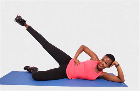 Smiling Woman on Yoga Mat Doing Side Lying Leg Raises