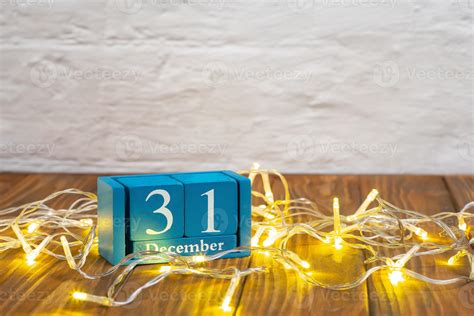 Wooden calendar with 31 december word on glowing garland background, New Year holiday 16231930 ...