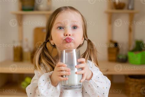 A cute little girl drinks milk at home in a wooden kitchen. Milk Day 20484026 Stock Photo at ...