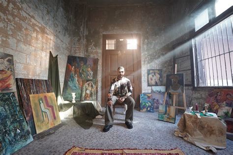 A man sitting in a room with paintings