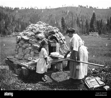 Life on the Indian reservation. Mom pulling bread out of a stone oven using a long wooden paddle ...