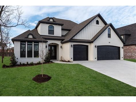 Painted Sherwin Williams Creamy brick house with board and batten over garage, black trim, black ...