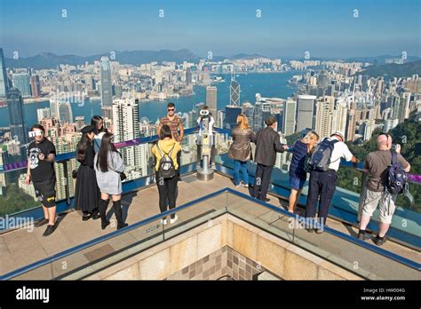 Tourists taking photographs from Sky Terrace 428 on top of the Peak Tower over Hong Kong and ...