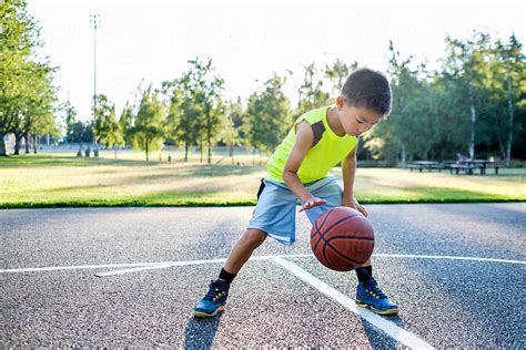 "Asian Kid Dribbling A Basketball In An Outdoor Basketball Court" by ...