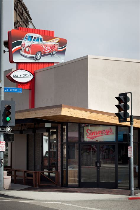 a red car sits on the roof of a building next to a traffic light and street sign