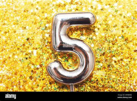 Five years birthday party. Festive silver big number five with golden confetti in the form of ...
