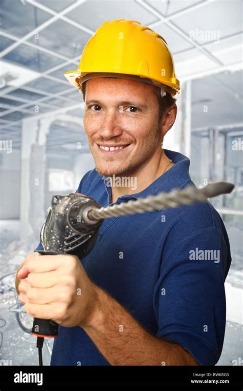 handyman holding electric drill and construction site background Stock Photo - Alamy