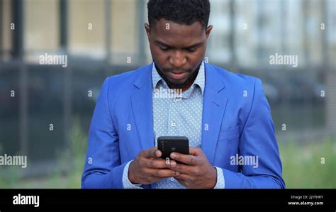 African American man types messages to workers on phone Stock Photo - Alamy