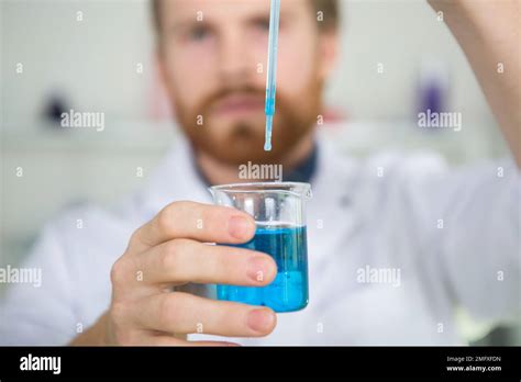 scientist dropping solution from pipette into flask Stock Photo - Alamy