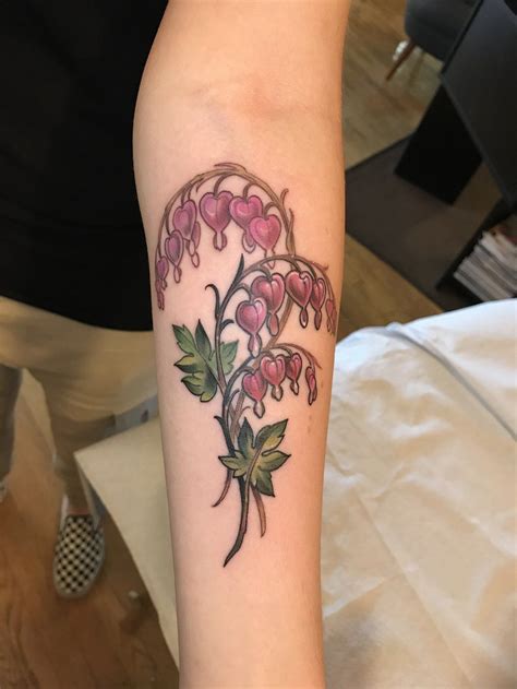 a tattoo on the arm of a woman with pink flowers and leaves around her neck