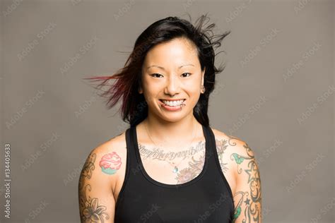 Athletic young asian woman with tattoos dressed in a black tank top and colored gym shorts ...