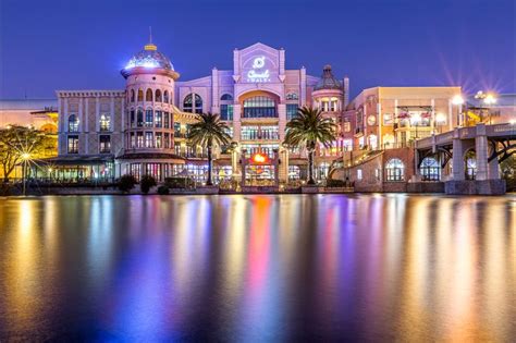 a large building that is lit up at night with lights reflecting off the water in front of it