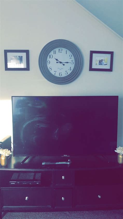 a flat screen tv sitting on top of a black entertainment center next to a wall mounted clock