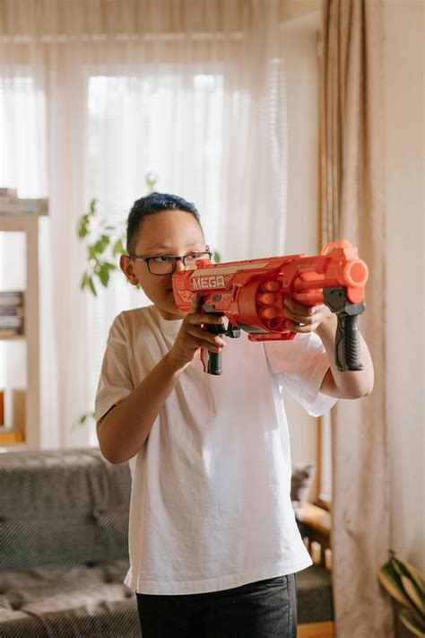 Man in White Crew Neck T-shirt Holding Red and Black Toy Gun · Free Stock Photo