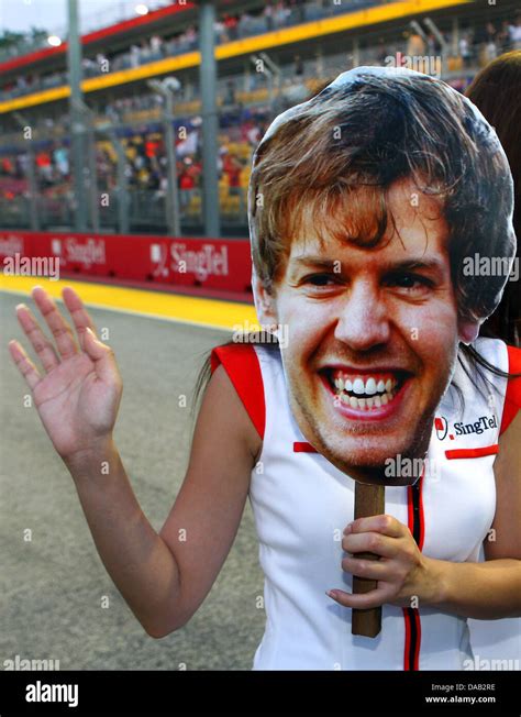 A grid girl holds a photo of German Formula One driver Sebastian Vettel of Red Bull during the ...