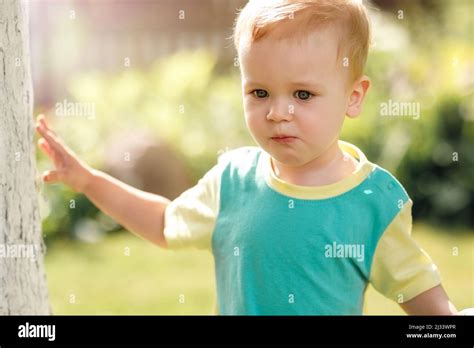 Portrait of a blond boy wearing a green t-shirt in the garden during the summertime Stock Photo ...