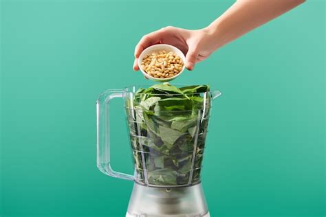 Premium Photo | Cropped view of woman adding pine nuts to basil leaves ...