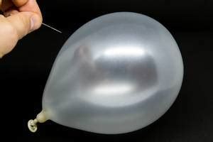 Hand uses a needle to burst a yellow balloon with 2023 text - Creative Commons Bilder