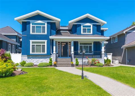 a blue house with white trim on the front and two story houses in the back