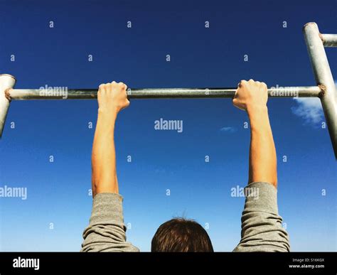 Man hanging on horizontal bar Stock Photo - Alamy