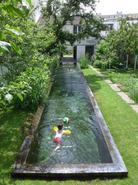 a long and narrow pool clad with stone is integrated right into the garden to make it feel ...