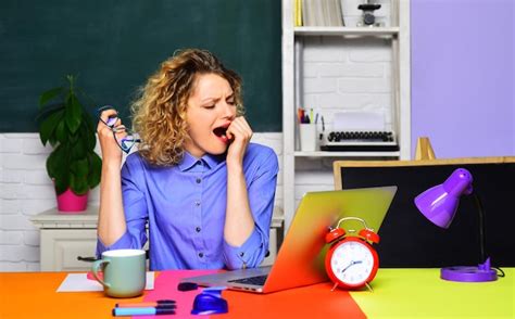 Premium Photo | Tired yawning teacher working with laptop in class hard work school professional ...