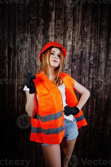 Engineer woman in orange protect helmet and building jacket against wooden background. 10495150 ...