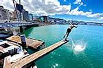 Wellington waterfront with teenagers jumping off a diving board near Frank Kitts Park and lagoon ...
