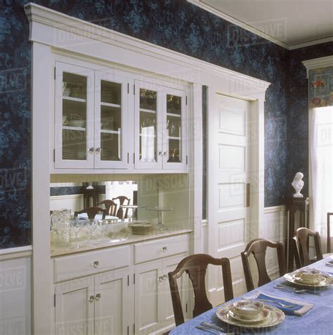 A built in china cabinet and buffet in a restored Victorian dining room, all wood is painted ...