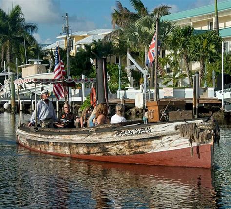 people are sitting in a boat on the water near some buildings and palm ...