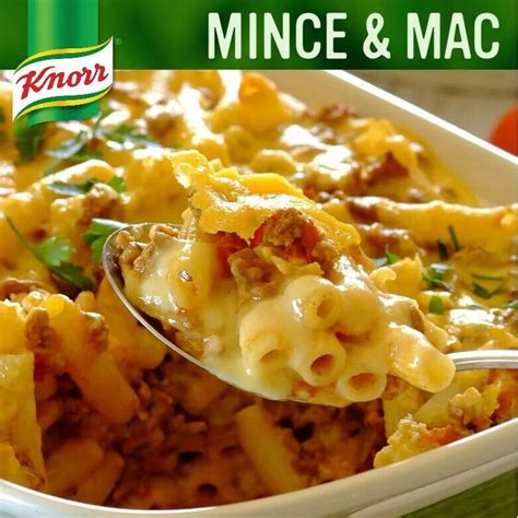 a green bowl filled with macaroni and cheese covered in sauce, meat and vegetables