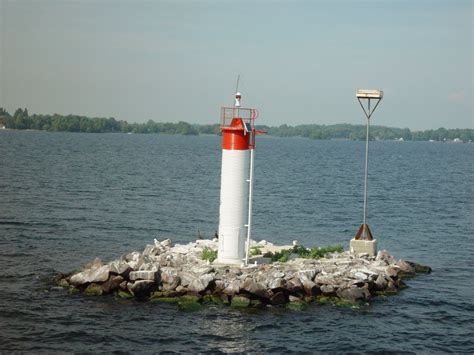 a red and white light tower sitting on top of a small island in the middle of water