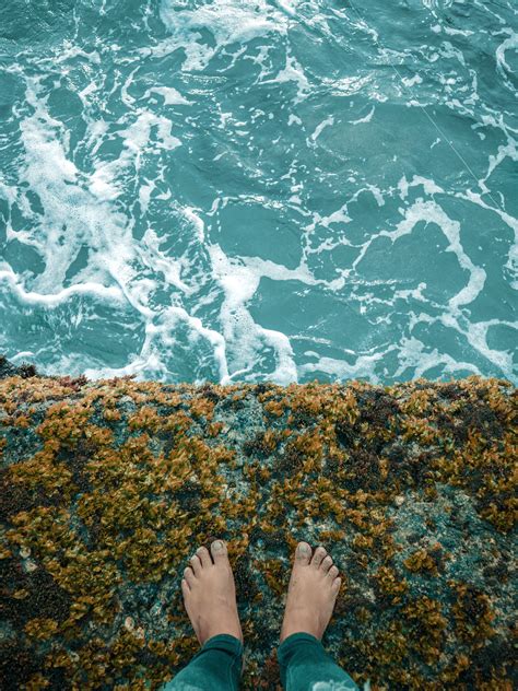 Person Standing on Cliff Overlooking Body of Water · Free Stock Photo