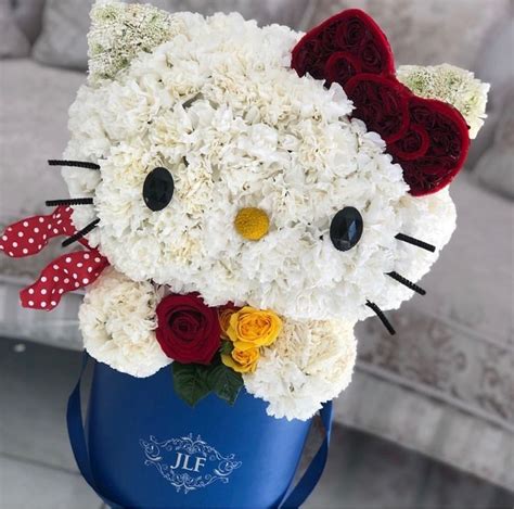 a hello kitty bouquet made out of white and red flowers in a blue vase with polka dots