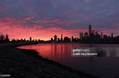 The sun rises behind the skyline of lower Manhattan and One World ...