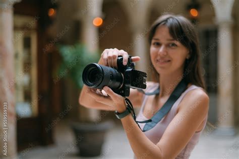 Girl photographer with a camera at work on the set in the studio room. Young beautiful woman - a ...